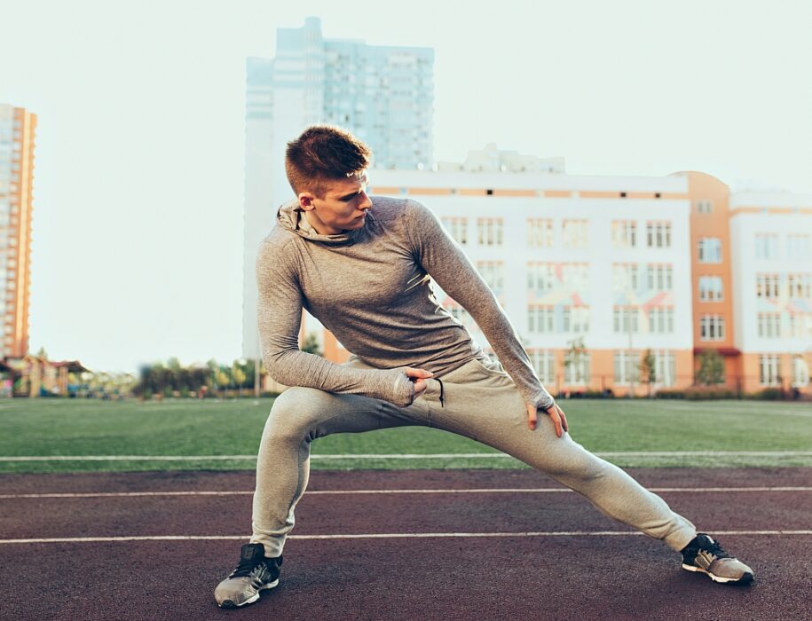 young sportive guy workout morning stadium he wears gray sport suit he is doing stretching