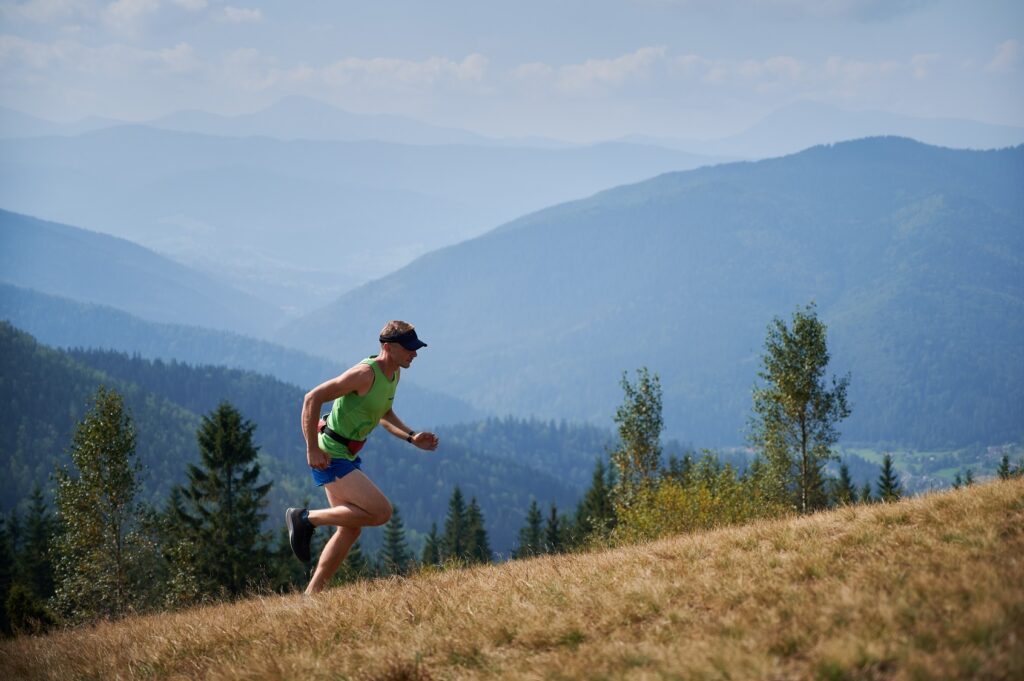 athletic young man running up hill mountains