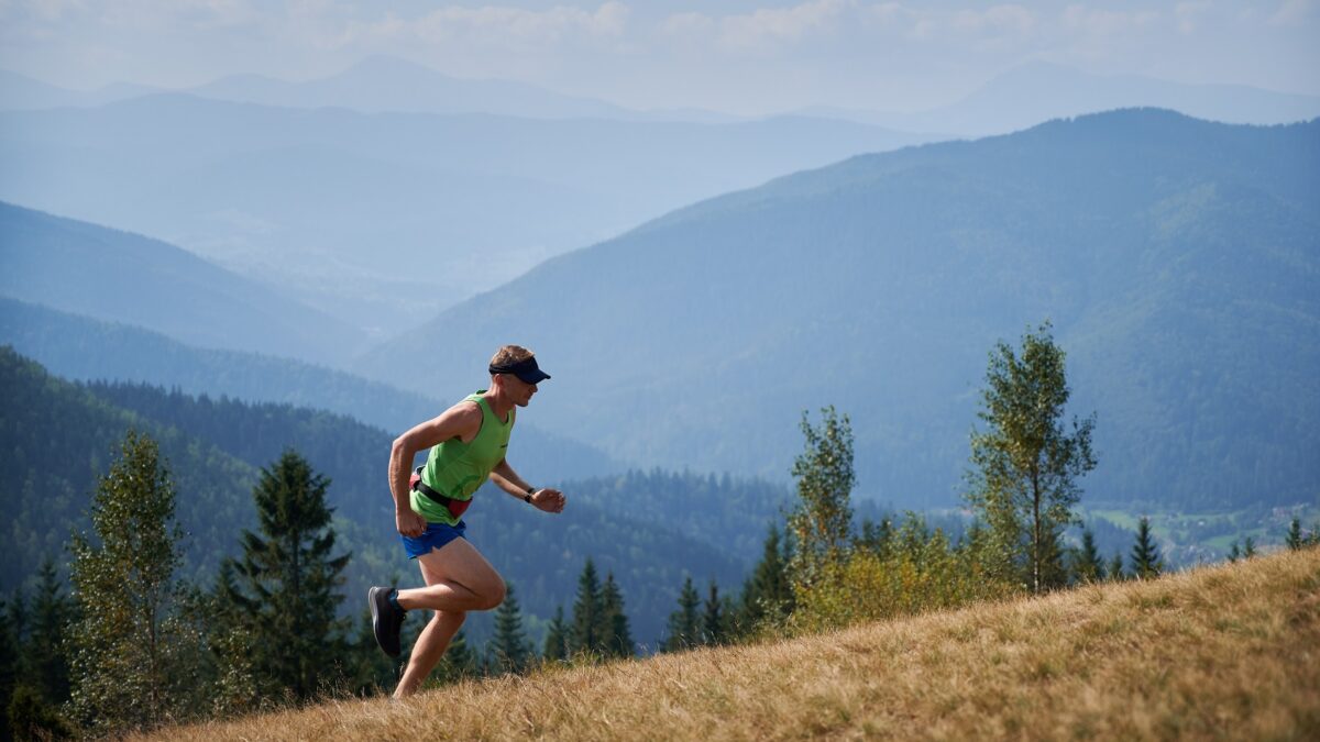 athletic young man running up hill mountains