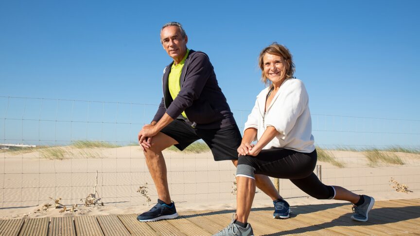 portrait happy elderly couple doing workout together caucasian man woman sportswear half sitting stretching legs smiling looking camera free time sport activity when retired concept