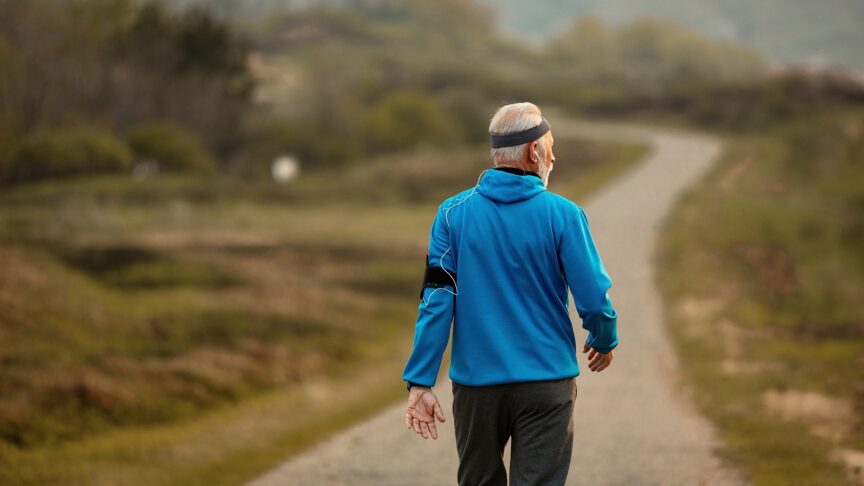 back view senior athlete walking road nature while keeping up his healthy lifestyle copy space