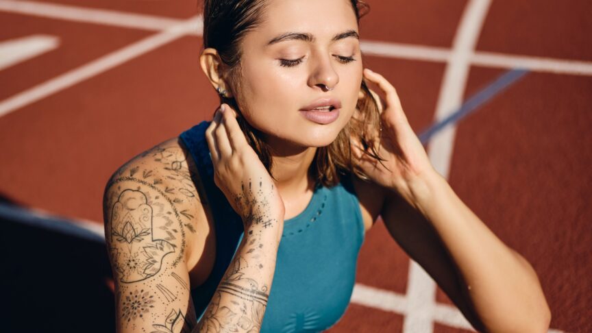 close up attractive wet athlete girl with tattooed hand sportswear dreamily resting after workout city stadium