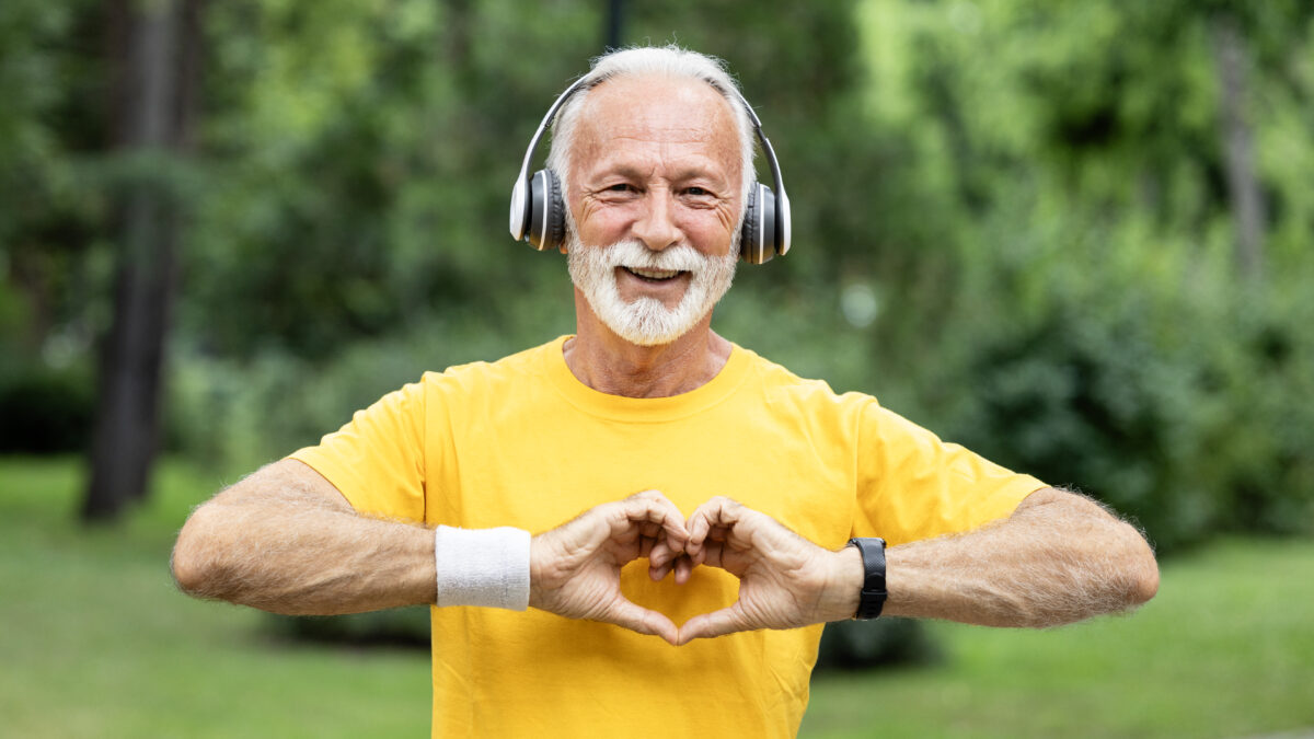 active senior man showing heart shape supporting healthy lifestyle retired man running outdoors